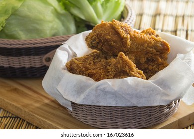 Fried Chicken in a basket on a wooden floor.
