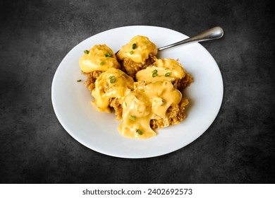 Fried chicken benedict topped with Hollandaise sauce. Chicken fried, Pumpkin sauce, butter on a white plate on a black background
