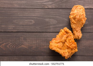 Fried chicken drumstick and chicken breast on the wooden background. Copyspace for your text.