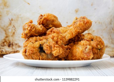 Fried chicken drumsticks on a white round plate, closeup. Side view. - Shutterstock ID 1139882291