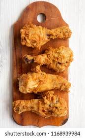 Fried Chicken Drumsticks On Wooden Board Over White Wooden Background, Top View. Overhead, Flat Lay, From Above. Close-up.