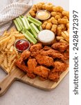 Fried chicken and french fries board with tater tots, fresh celery and dipping sauces