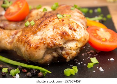 Fried chicken legs garnish cherry tomato and spring onions on black slate board - Shutterstock ID 557659459