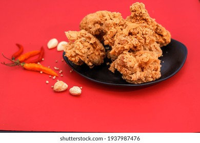 Fried Chicken On Black Plate With A Red Isolated Background. Ayam Goreng.