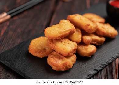 Fried chicken pieces on stone board with chopsticks - asian food close-up - Shutterstock ID 2250692847
