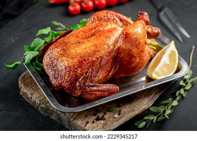 Fried chicken served on a tray whole. Oven-cooked chicken with a meat fork on a wooden board - Shutterstock ID 2229345217