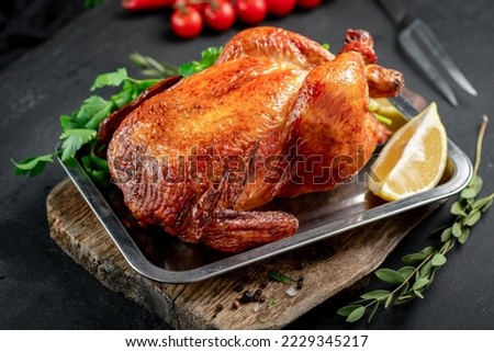 Fried chicken served on a tray whole. Oven-cooked chicken with a meat fork on a wooden board