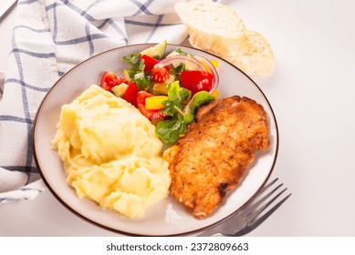 Fried chicken steak or schnitzel with mashed potatoes and vegetables salad in plate on white table 