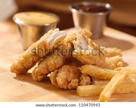 fried chicken strips with french fries and sauce.