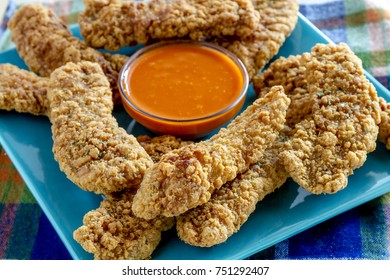 Fried Chicken Strips On Blue Square Plate With Hot Buffalo Wing Dipping Sauce In Center