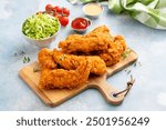 Fried chicken tenders on a serving board served with sauces and salad