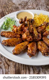 Fried Chicken Wings And Legs In A Sauce With Mustard Peas, Shoots, Mung Bean Salad, Sauce On A White Round Plate. Vertical Orientation