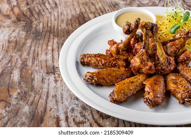 Fried Chicken Wings And Legs In A Sauce With Mustard Peas, Shoots, Mung Bean Salad, Sauce On A White Round Plate. Horizontal Orientation