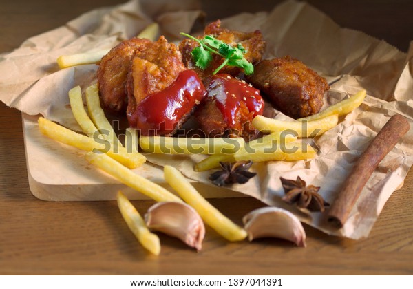 Fried chicken\
wings with spices and tomato sauce or ketchup and french fried on\
Eco brown paper.Delicious fast food and hi trans fat and\
cholesterol.Concept of trans fat\
food.