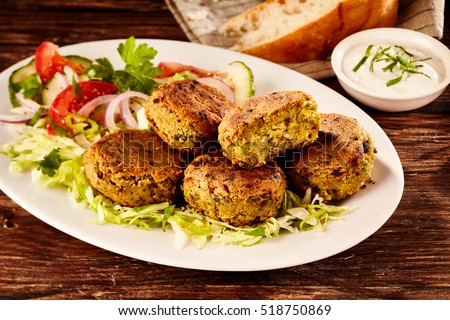 Fried chickpea and fava bean patties, or falafel, served on a large platter with fresh salad and sour cream for tasty Turkish cuisine Stock photo © 