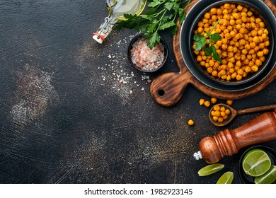 Fried chickpeas with turmeric with parsley and lime in black plate on an old black table background. Roasted spicy chickpeas or Indian chana or chole, popular snack recipe. Top view. - Shutterstock ID 1982923145
