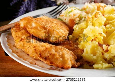 Fried cod fillet in breadcrumbs served with boiled potatoes and vegetable salad..