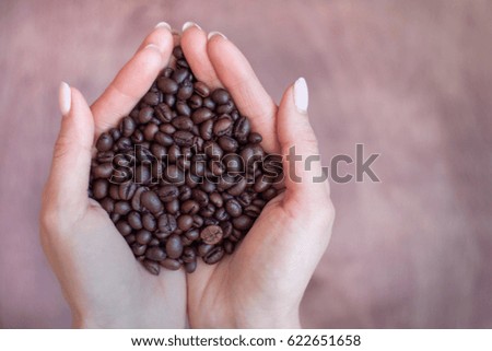Fried coffee beans in the palm of a young woman