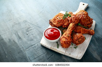 Fried Crispy Chicken Legs, Thigh On White Cutting Board With Ketchup And Herbs