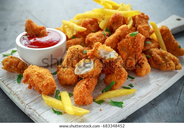 Fried crispy chicken nuggets with french fries and\
ketchup on white board