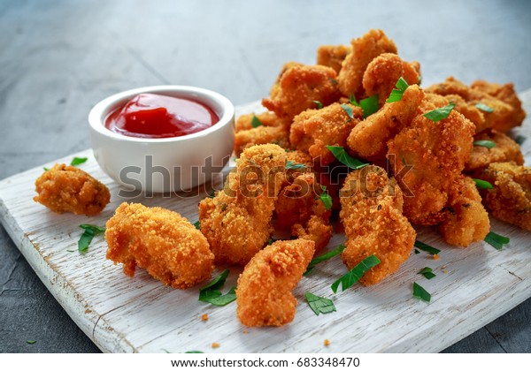 Fried\
crispy chicken nuggets with ketchup on white\
board