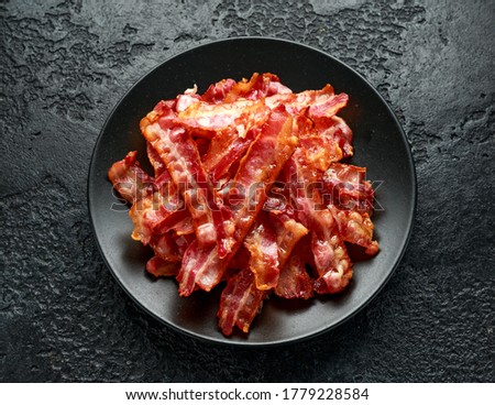 Fried crunchy Streaky Bacon pieces in a black plate