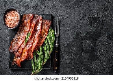Fried crunchy Streaky Bacon stripes. Black background. Top view. Copy space