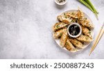 Fried dumplings gyoza with soy sauce, and chopsticks, top view.