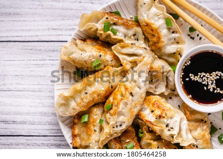 Fried dumplings gyoza with soy sauce, and chopsticks, top view.