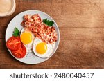 Fried Egg and Bacon on plate for breakfast and cup of coffee on wooden background, copy space. Keto breakfast with egg, vegetables and bacon top view.