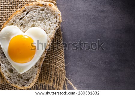 Fried egg on heart-shaped slice of bread.