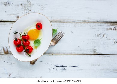 Fried egg, roasted cherry tomatoes, fresh basil and spices on ceramic plate for delicious breakfast over white wooden backdrop, top view, horizontal. Healthy, clean eating, dieting food concept - Shutterstock ID 622412633