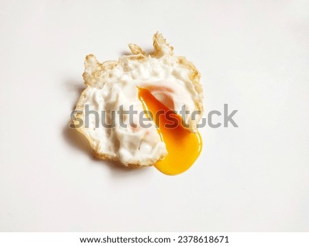 A fried egg with runny yolk sits on a white background.
