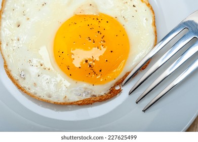 Fried Egg Sunny Side Up On A Plate With Fork Over Wood Table