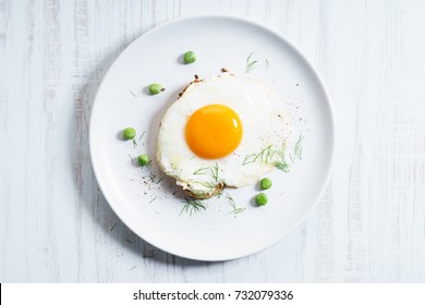 Fried Egg With Toasted Bread Decorated With Green Pea On White Plate. Breakfast Dish.