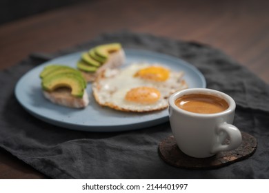 fried egg with two avocado sandwiches and espresso for breakfast on a blue plate - Powered by Shutterstock