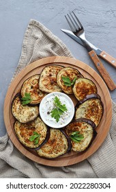Fried eggplant on a wooden plate on a gray background. Vegetable appetizer of eggplant. Top view. Vertical photo.