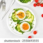 Fried eggs, avocado and greens on bread over stone background with copy space. Top view, flat lay. 