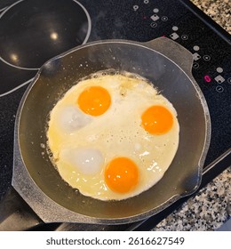 Fried Eggs Being Skillfully Cooked in a WellUsed Cast Iron Skillet for a Hearty Breakfast