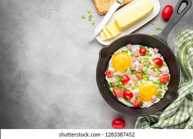 Fried Eggs In Black Pan With Ham, Cherry Tomatoes And Spring Green Onions. Delicious Breakfast With Toast And Butter. The Classic English Lunch. Copy Space