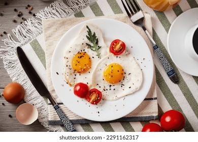 Fried eggs for breakfast. Healthy breakfast with vegetables and herbs. Fried eggs on a white plate. Serving on the table. Morning fried eggs with coffee and orange juice.
