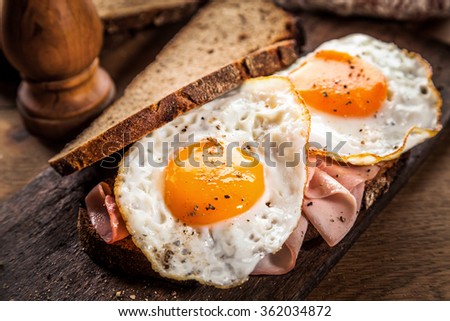 Fried eggs and ham served on healthy wholegrain bread for breakfast in a rustic kitchen or restaurant