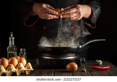 Fried Eggs Or Scrambled Eggs Are Prepared By The Hands Of The Chef. A Novice Cook Practices In The Kitchen Of A Restaurant