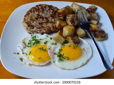 Fried Eggs Top With Parsley And Served With Sausage Patty And Home Fries,