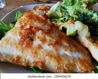 Fried fish. Breaded walleye fillet. Garnish with broccoli and green vegetables. Home dinner. 
Close-up photo 