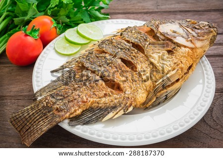 Fried fish on plate with vegetables
