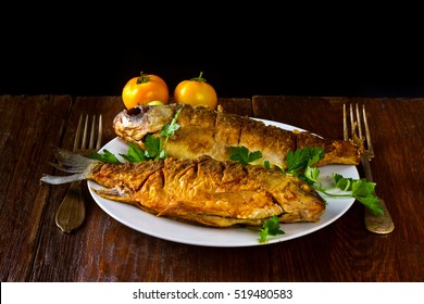 fried fish on a white plate on a wooden background