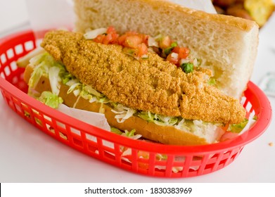 Fried fish or po boy sandwich. Classic Cajun cuisine: fried fish sandwich served on toasted bun with onions, lettuce, tomato, mayo, salt and pepper. Classic New Orleans sandwich favorite.
