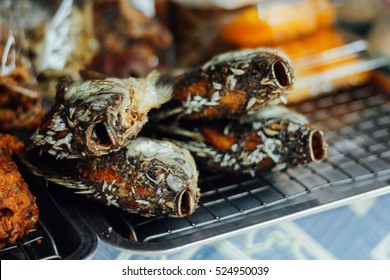 Fried Fish For Sale For People To Buy At An Asian Food Market In The Hot Eat. The Fried Fish Are Covered In A Slat Type Seasoning. Four Dead Fish Lying On A Silver Grill. Food At Grocery Store. 