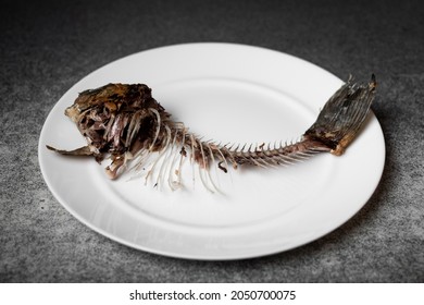 Fried Fish Skeleton, Spine And Bones On A White Plate.